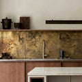 Antique brass splashback with aged patina in Japandi kitchen interior with wooden cabinets, a white stone countertop island, and stainless steel worktop