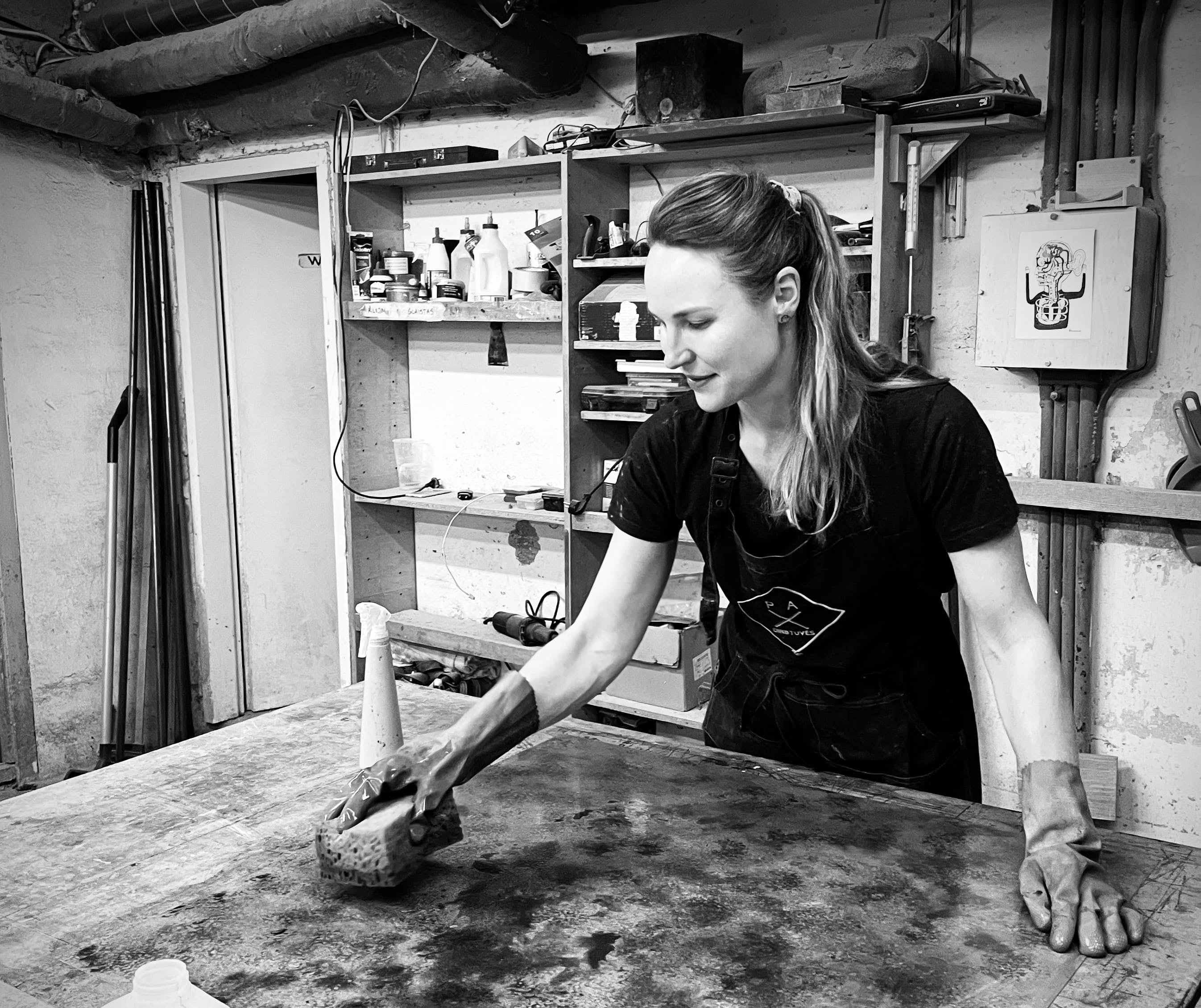 A young female artist working on a sheet of metal in a workshop environment