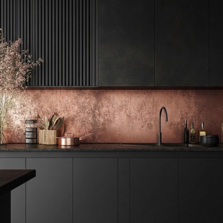 Bespoke copper splashback in all-black sleek modern kitchen with black matte cabinets, dark marble countertops and black tap