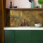 Modern kitchen with green cabinets, concrete countertop, and textured aged brass backsplash with verdigris accents