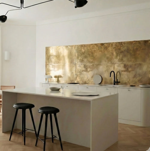 Custom aged brass kitchen splashback with textured patina finish, installed in a modern luxury kitchen with white cabinets and a kitchen island